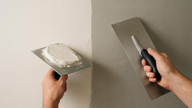 Szpachlowanie ściany szeroką pacą, połowa ściany już gładka